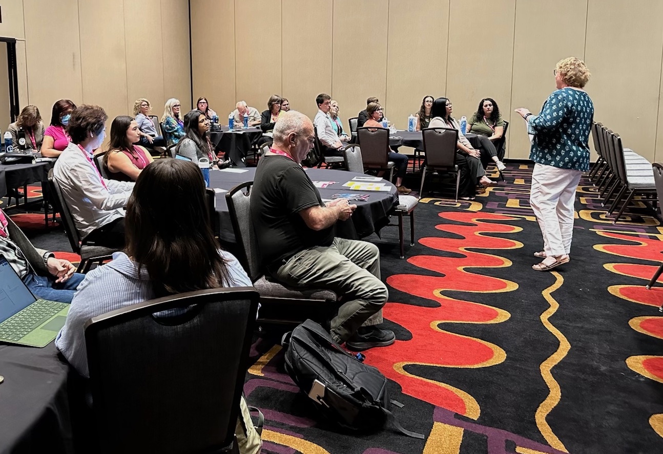 A room full of journalists listens to Joy Mayer speak in a hotel conference room.